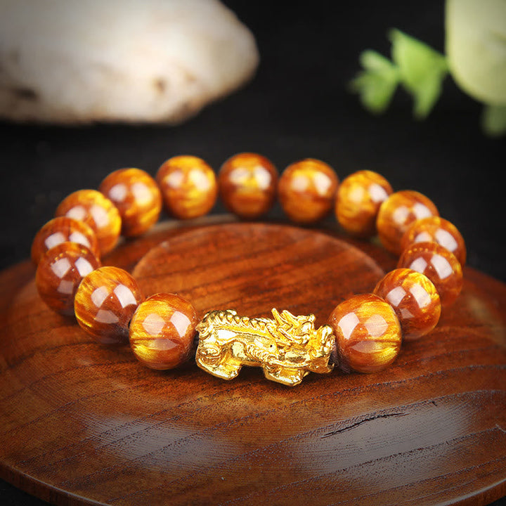 Bernstein Tigerauge Armband mit goldener Pixiu Figur auf Holz