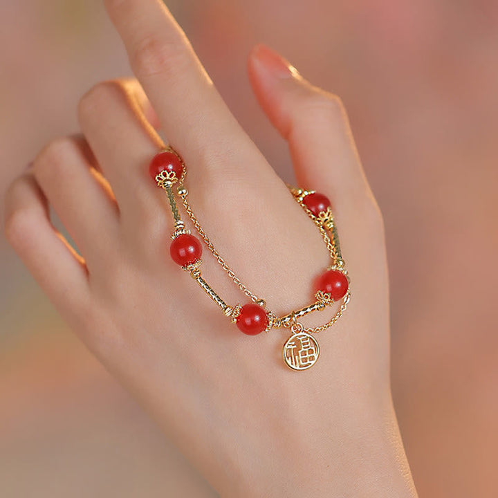 Armband Roter Achat Fu-Zeichen am Handgelenk mit goldenen Elementen getragen