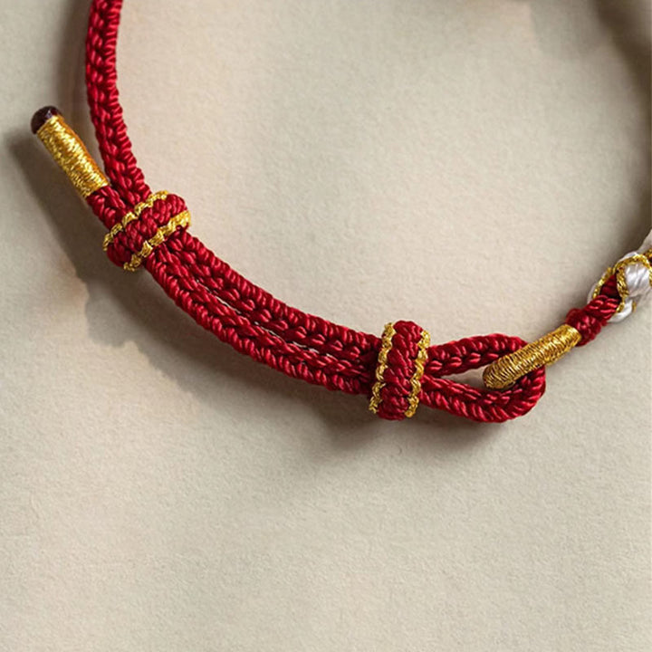Rotes Armband Pfirsichblüte mit goldenen Perlen elegant getragen.
