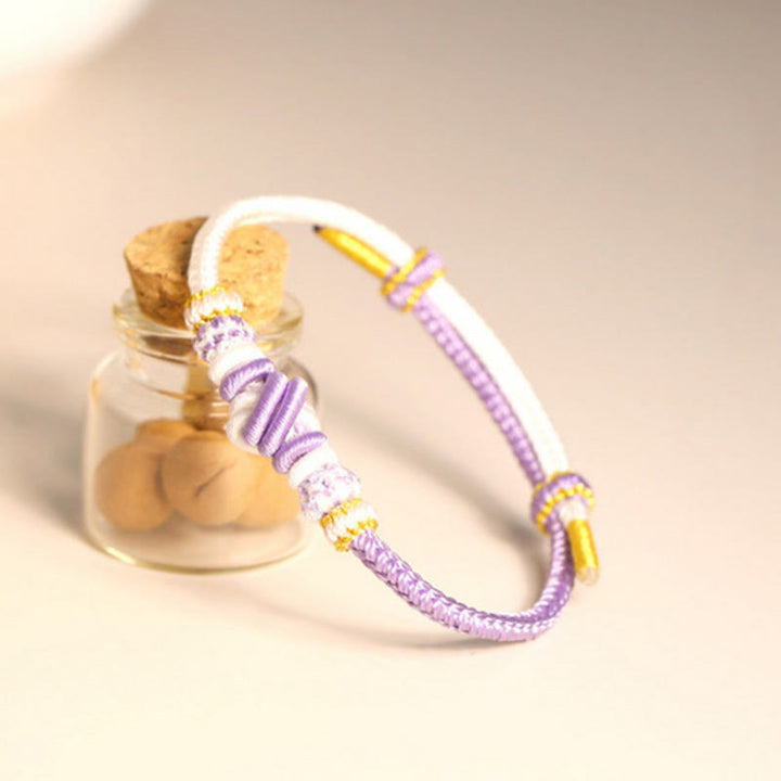 Armband – Glück & Frieden mit lila Schnur und goldenem Zubehör elegant.