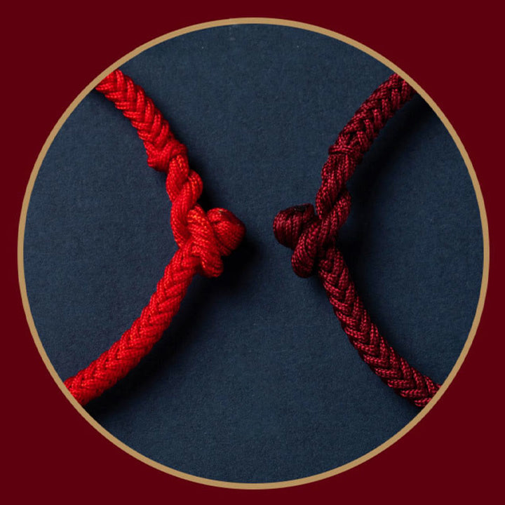 Rotes Seilarmband mit Knoten auf dunkelblauem Hintergrund elegantes Design.