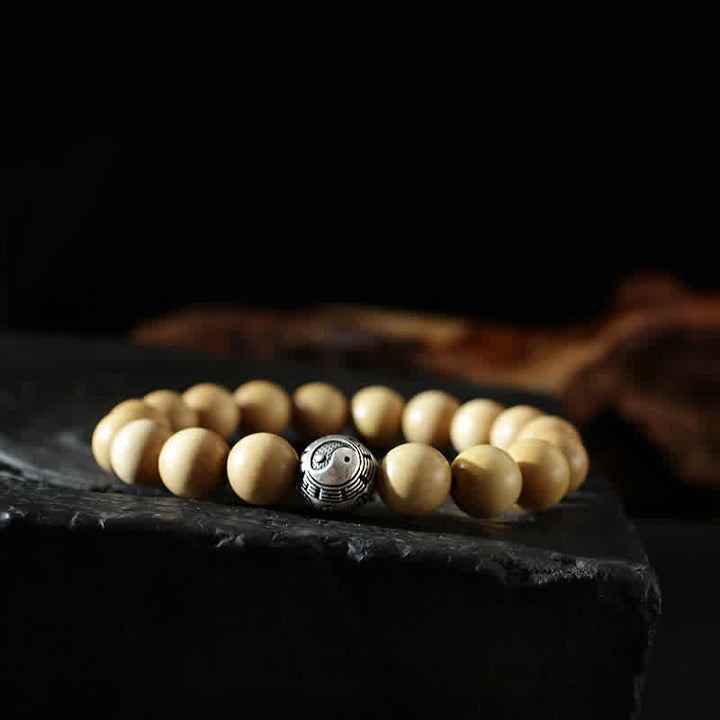 Armband Zinnober Yin Yang mit cremefarbenen Perlen auf schwarzem Stein.