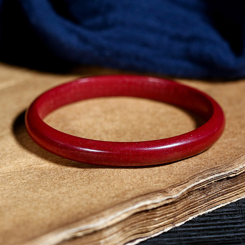 Rotes Zinnober Armband Herzsutra – Segen elegant auf Holz präsentiert.