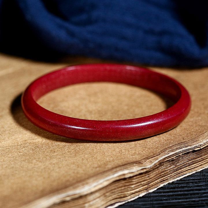 Rotes Zinnober Armband Herzsutra – Segen elegant auf Holz präsentiert.