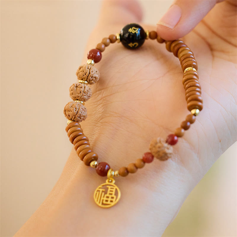 Armband mit schwarzem Onyx, Bodhi-Perlen und goldenem Om-Anhänger am Handgelenk.
