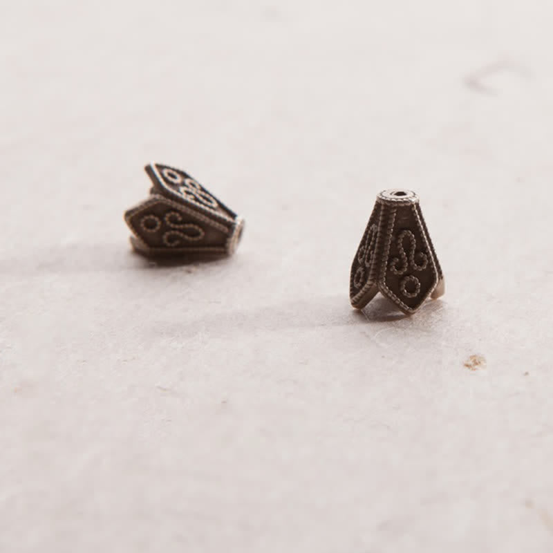 Zwei bronzefarbene Mala-Perlen mit ornamentalen Mustern auf weißem Hintergrund.
