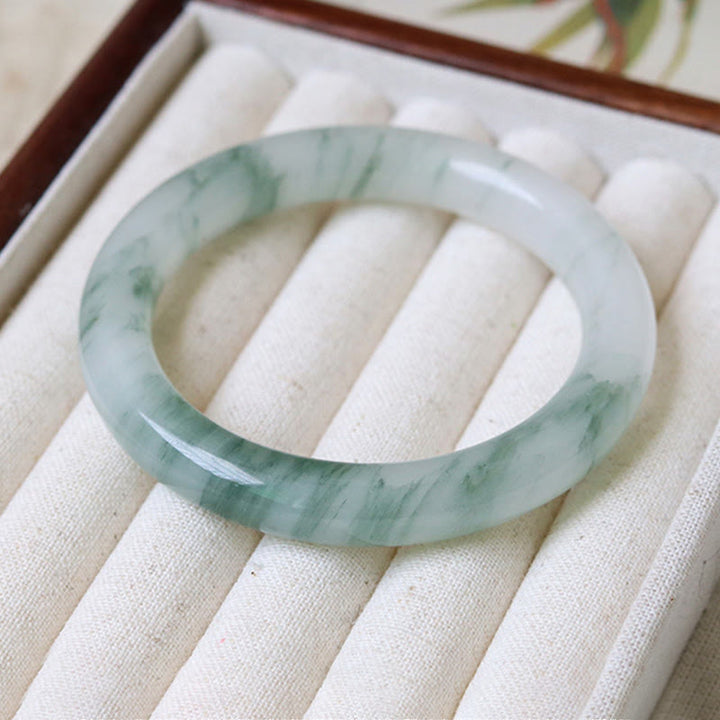 Jade Armband mit grünen Mustern auf beiger Leinenoberfläche elegant präsentiert