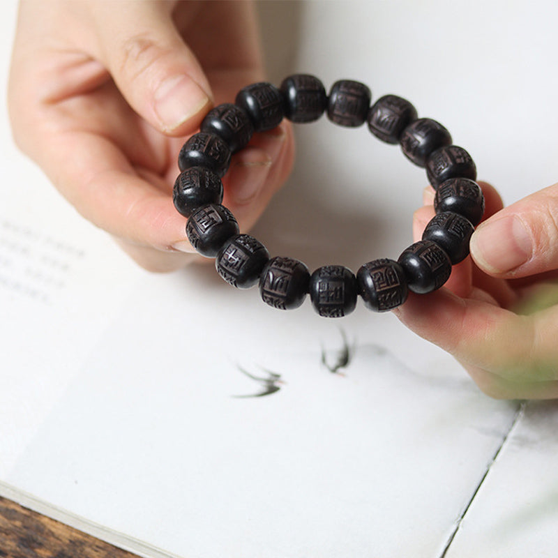 Schwarzes Ebenholz Armband mit Om Mani Padme Hum Symbolen an Hand.