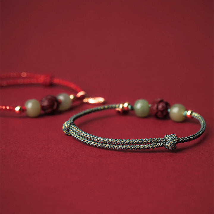 Armband Zinnober Jade Lotus – Glück mit Perlen auf rotem Hintergrund