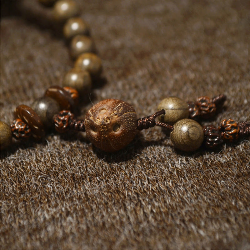 Mala Sandelholz – Schutz Armband mit braunen Perlen auf Stoff.