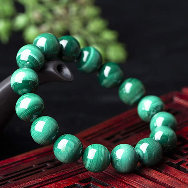Mala Malachit Armband grüne Kugeln Naturstein auf rotem Holz Nahaufnahme