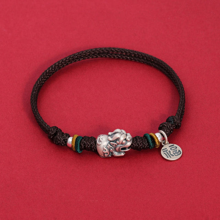 Schwarzes Armband mit silbernem Fu-Zeichen Charm auf rotem Hintergrund.