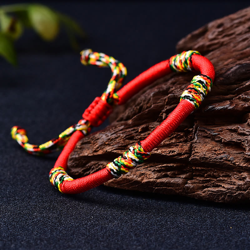 Rotes Armband mit bunten Wicklungen auf Holz, Schutz & Glück Balance Armband.