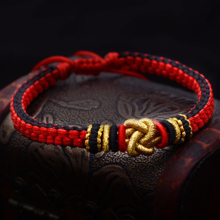 Rotes Armband – Glück & Liebe mit goldenen Verzierungen auf Holz.