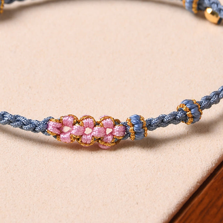 Armband Pfirsichblüte – Schutz rosa Perlen blaue Schnur elegant getragen