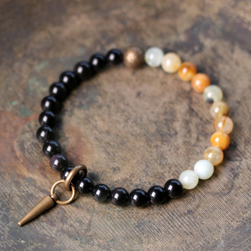 Schwarzer Obsidian Armband mit weißen Perlen und Bronzeanhänger elegant.