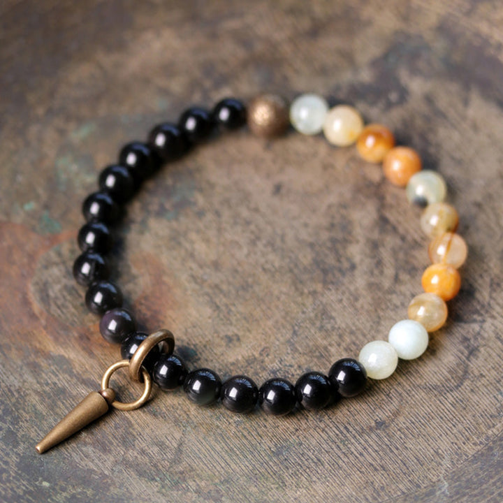 Schwarzer Obsidian Armband mit weißen Perlen und Bronzeanhänger elegant.