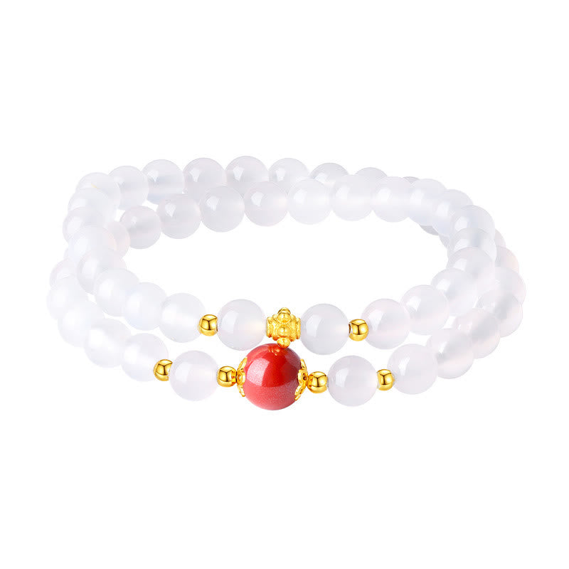Weißes Perlenarmband mit rotem Zinnober Stein und goldenen Akzenten.