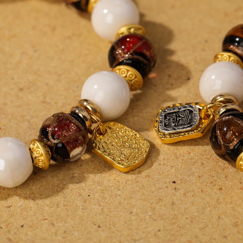 Armband – Schutz & Wohlstand & Balance mit weißen Perlen und goldenen Elementen.