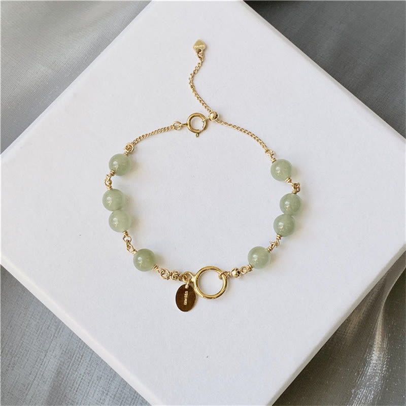 Jadegrünes Armband mit goldenen Elementen und Anhänger elegant präsentiert.