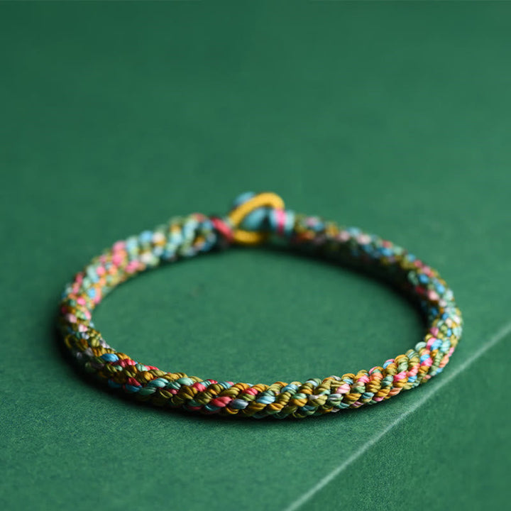 Buntes geflochtenes Armband Glück mehrfarbig Schnur Grün Hintergrund.