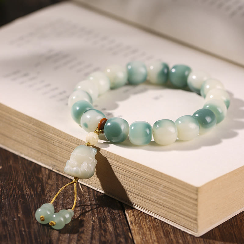 Grünes Jade Armband mit weißen Perlen und Anhänger auf Buch