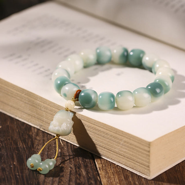 Grünes Jade Armband mit weißen Perlen und Anhänger auf Buch