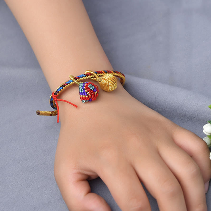 Buntes Armband mit goldenen Glückszongzi-Anhängern am Handgelenk getragen