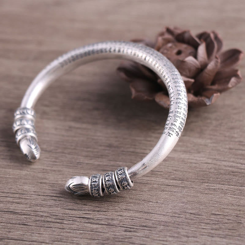 Silbernes Om Mani Padme Hum Armband mit strukturiertem Design auf Holzoberfläche.