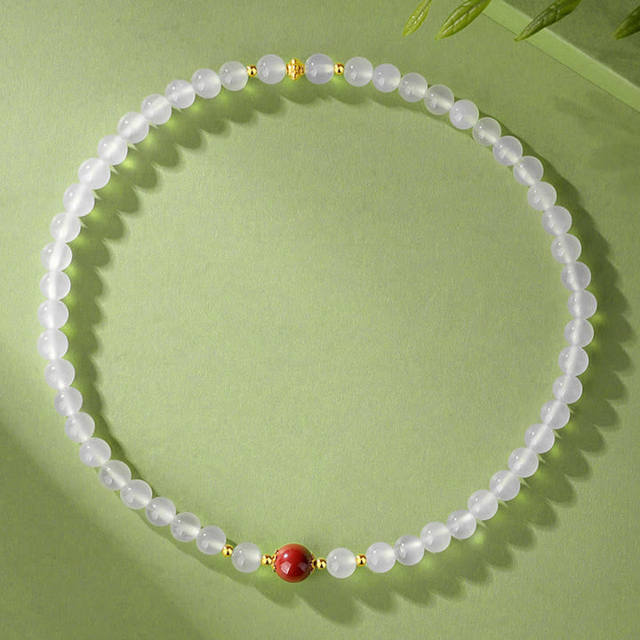 Elegantes Armband mit weißen Perlen und rotem Zinnober Schutzstein.
