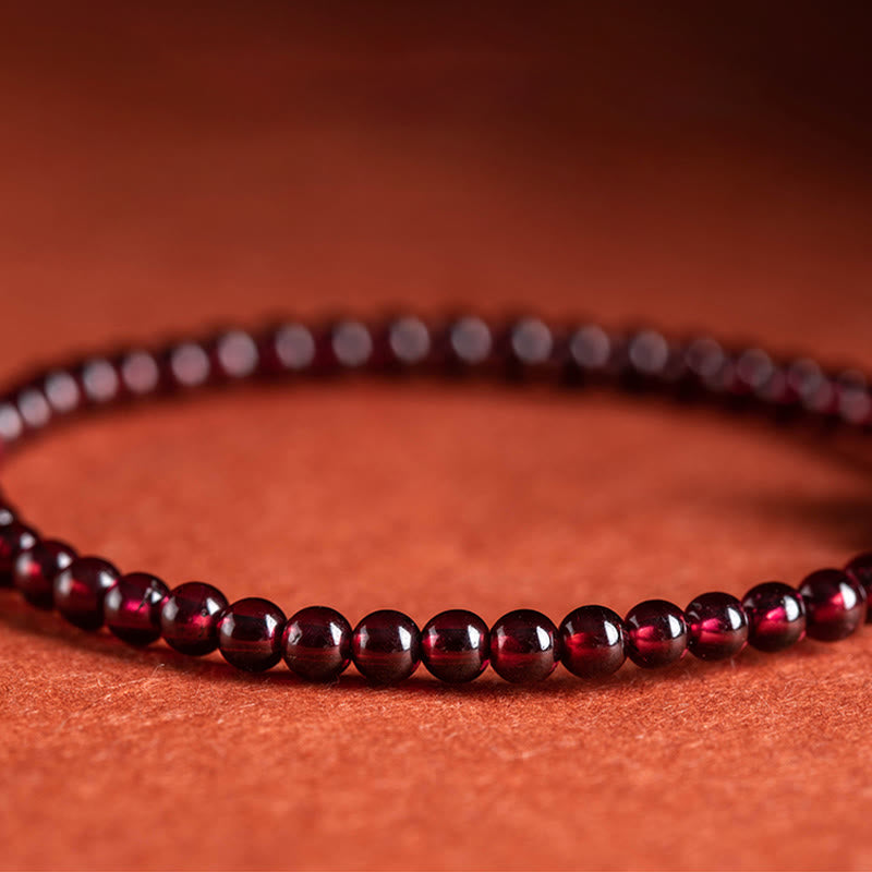 Zinnober Granat Armband mit glänzenden roten Perlen auf orangefarbenem Hintergrund elegant.