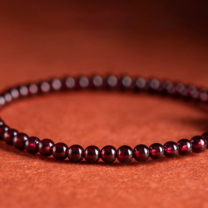 Zinnober Granat Armband mit glänzenden roten Perlen auf orangefarbenem Hintergrund elegant.