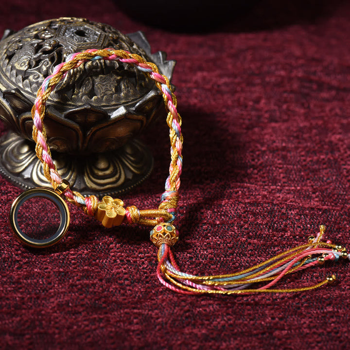 Buntes Tibet Glück Armband mit Quasten auf rotem Hintergrund.