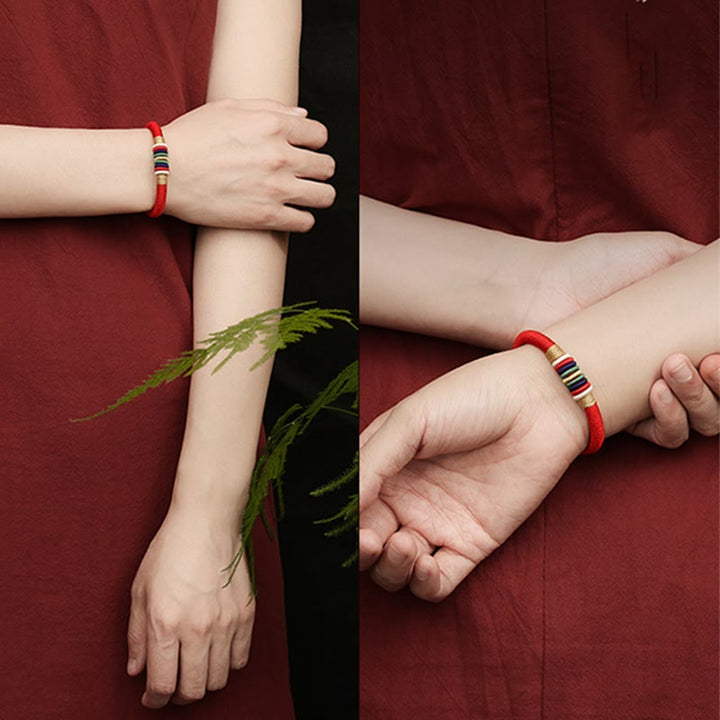 Rotes Armband Fünf Elemente – Glück & Energie an weiblichem Handgelenk getragen.