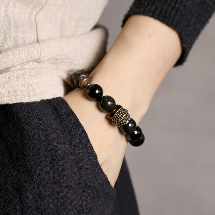 Schwarzer Obsidian Armband mit Kupfer Details elegant am Handgelenk getragen.