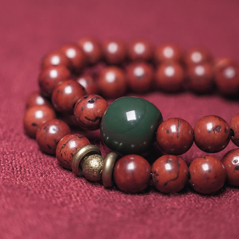 Armband Cyan Jade Kupfer mit roten Perlen auf rosa Untergrund.