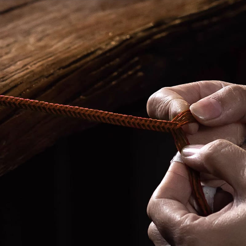 Rotes Seidenarmband mit Knoten wird von Hand geknüpft zusammengebunden