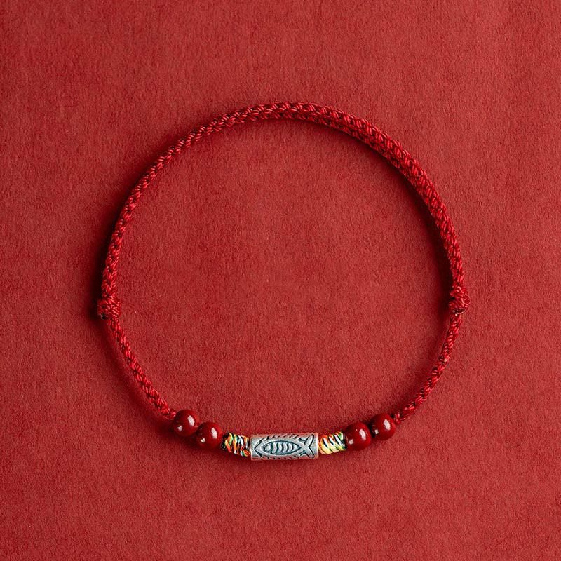 Rotes Armband mit Silber Koi Fisch Anhänger auf rotem Hintergrund.