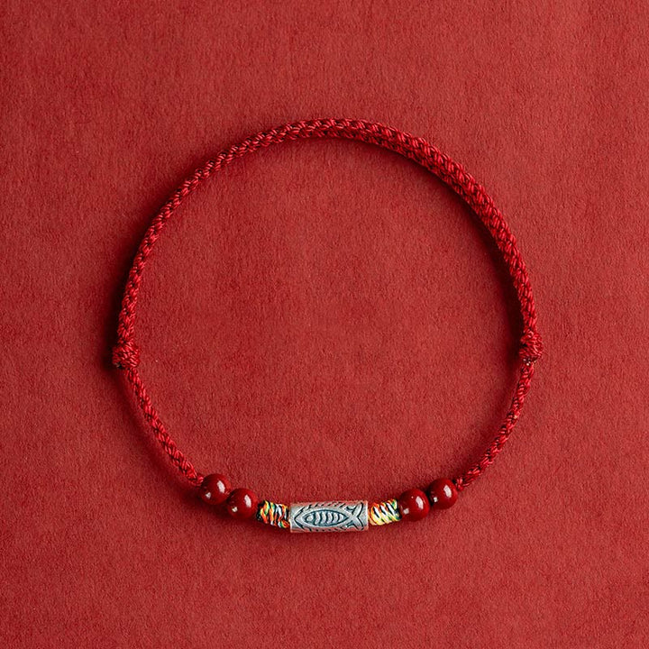Rotes Armband mit Silber Koi Fisch Anhänger auf rotem Hintergrund.
