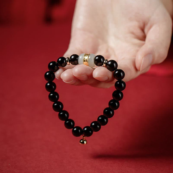 Schwarzes Obsidian Armband mit weißem Jade-Element elegant am Handgelenk getragen.