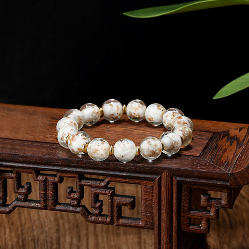 Weißes Armband mit Goldakzenten auf Holzoberfläche elegant präsentiert
