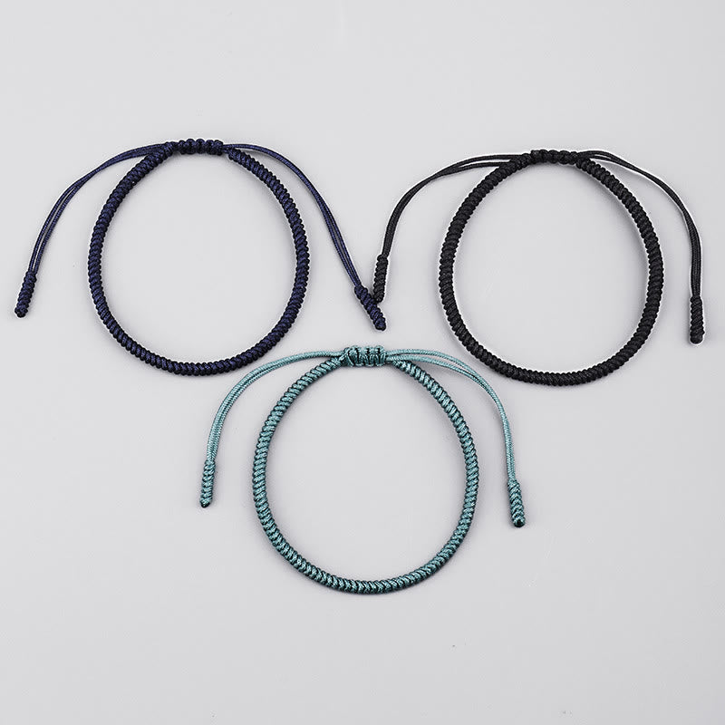Drei geflochtene Armbänder in Blau, Schwarz und Türkis auf weißem Hintergrund.