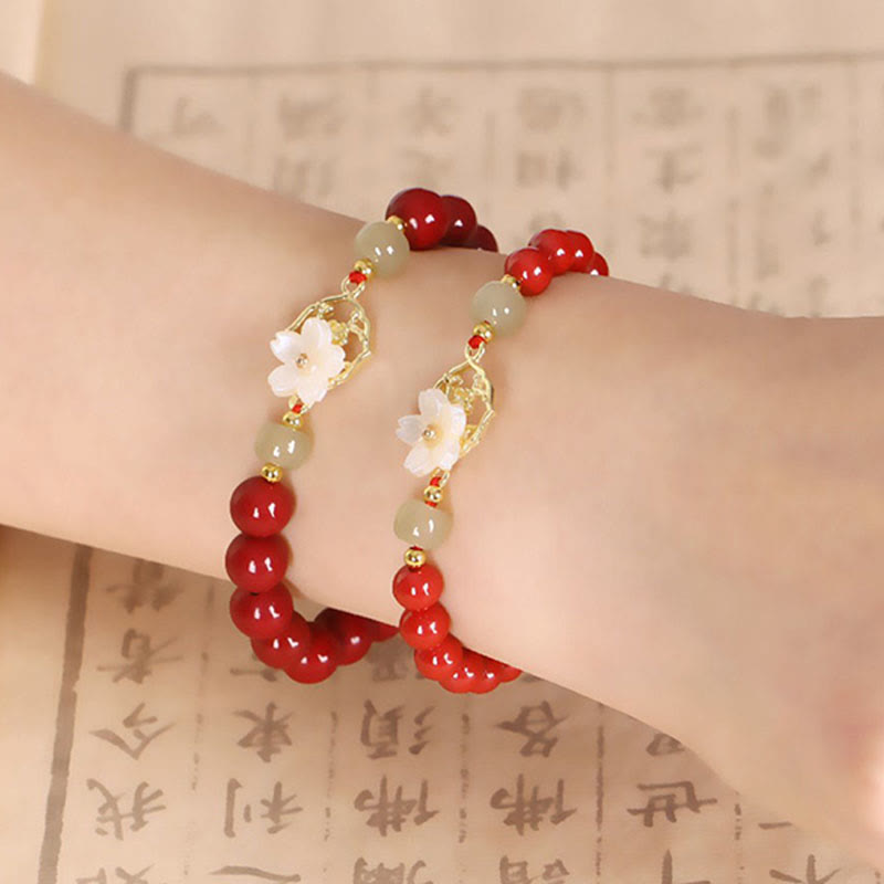 Armband Zinnober Jade – Segen mit weißen Blüten am Handgelenk getragen