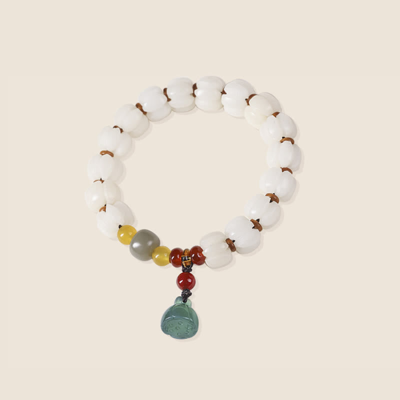 Armband mit weißen Perlen, Achat und grünem Anhänger elegant präsentiert.
