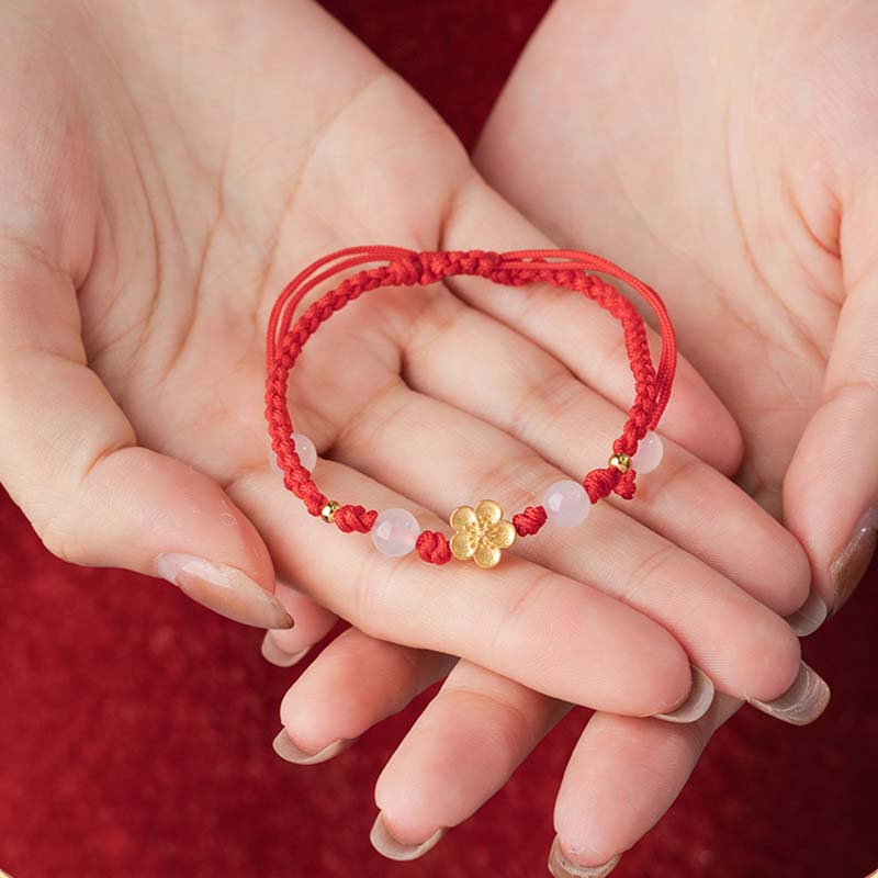 Rotes Armband mit Pfirsichblüte Charm elastisch am Handgelenk getragen
