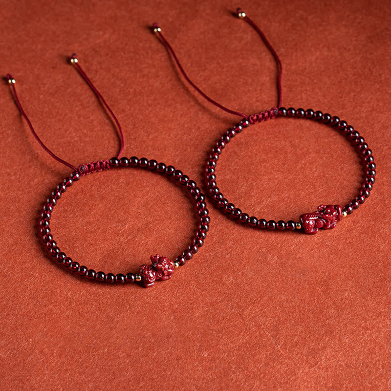 Zwei rote Granat Pixiu Armbänder auf terrakottafarbenem Hintergrund elegant präsentiert