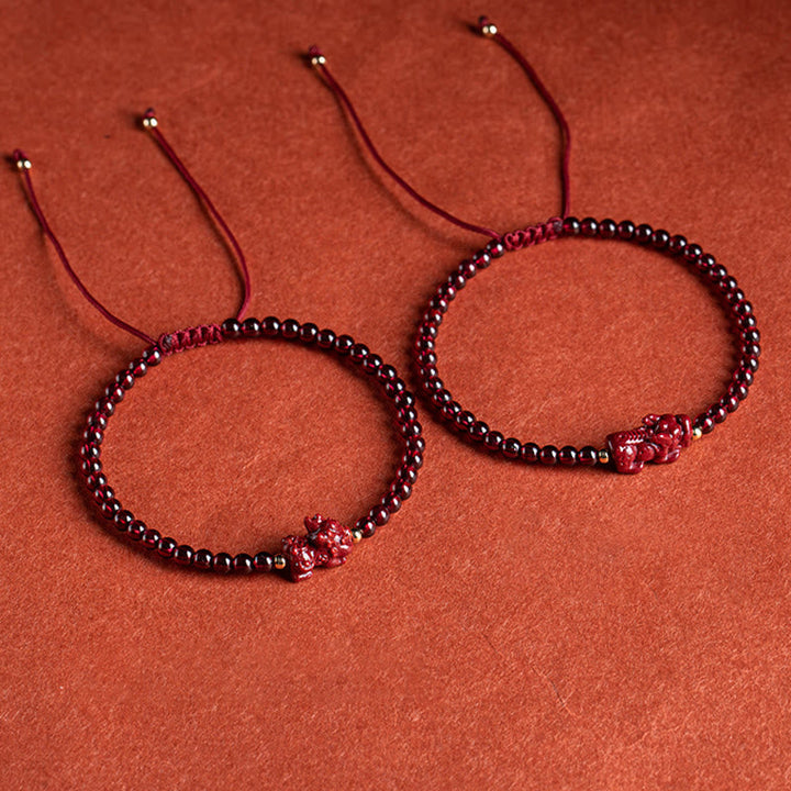 Zwei rote Granat Pixiu Armbänder auf terrakottafarbenem Hintergrund elegant präsentiert