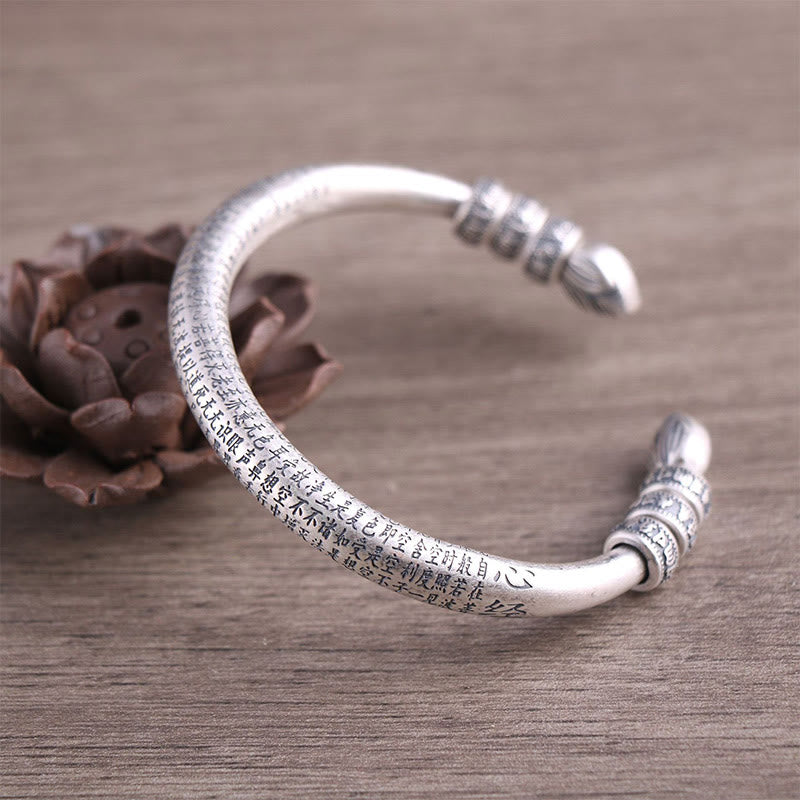 Silbernes Om Mani Padme Hum Armband mit Gravur auf Holzoberfläche.