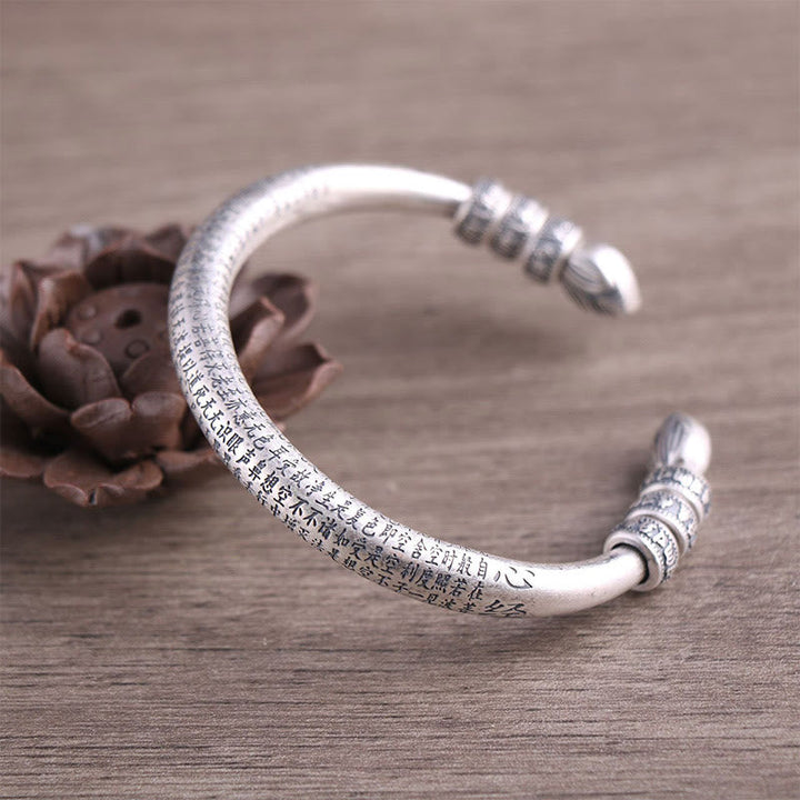 Silbernes Om Mani Padme Hum Armband mit Gravur auf Holzoberfläche.