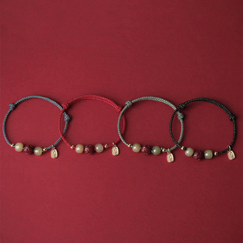 Vier Armbänder mit Perlen und Lotus-Anhängern auf rotem Hintergrund.